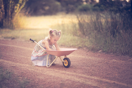 Little girl playing in a park with a wheelbarrowの写真素材