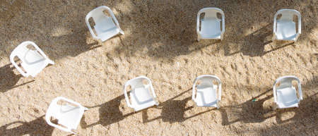 Eight empty chairs on the sand waiting to be occupied in a show