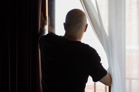 Man locked up at home. Looking through the window. Covid coronavirus quarantine
