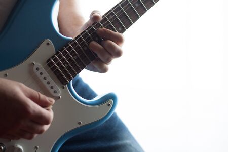 Close-up of man playing blue and white electric guitar