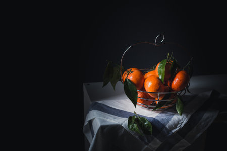 Fresh tangerines with leaves in a basket on a dark backgroundの写真素材