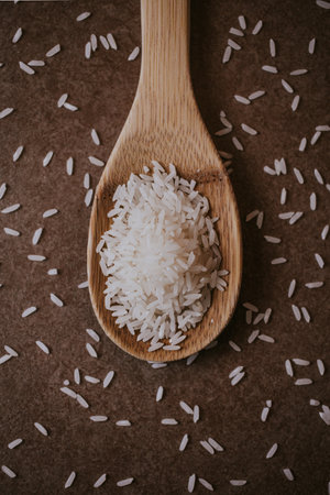 Rice in a wooden spoon on a brown background. Selective focus.の写真素材