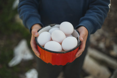 Close-up of man holding bowl with chicken eggs in the countryside