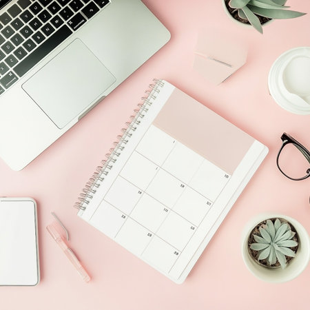 Flat lay office desk workspace with laptop, smartphone, coffee cup, notebook, stationery and copy space on pink background. Top view feminine workplace concept.の素材