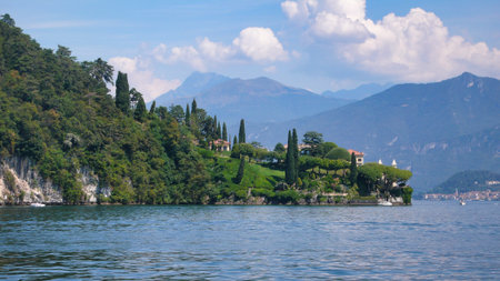 Villa del Balbianello on the Shore of Lake Como. The elegant Villa del Balbianello, perched on a scenic peninsula overlooking the calm waters of Lake Como. The historic building is framed by lush terraced gardens and the majestic Italian Alps, creating a picturesque and iconic travel destination.の写真素材
