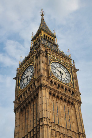 Iconic Big Ben clock tower against a blue sky: A detailed close-up of London's famous landmark, emphasizing its intricate golden and weathered stonework.の写真素材