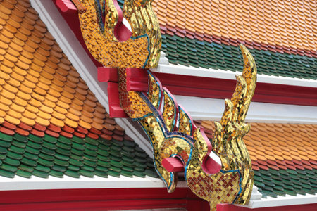 Thai palace roof with intricate details - A close-up shot of the ornate, golden-tiled roof and sculpted dragon details on a building at Bang Pa-In Royal Palace, Thailand.の写真素材