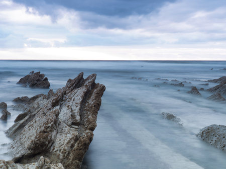 Misty seascape at a rocky beach in the Basque Country - A long exposure of the ocean smoothing over...