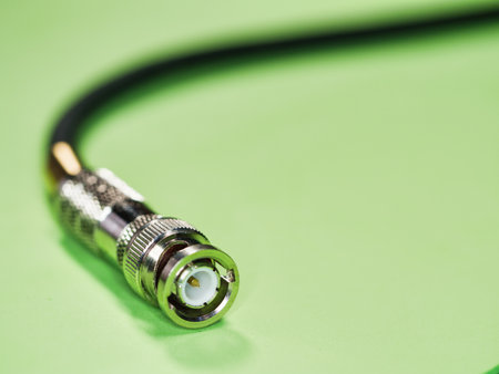 BNC connector at the end of a black cable - A detailed close-up of a shiny BNC connector attached to...