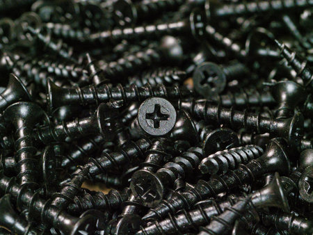 Macro view of black drywall screws background - A detailed, close-up view of a pile of black drywall...