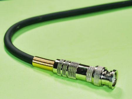BNC connector at the end of a black cable - A detailed close-up of a shiny BNC connector attached to...