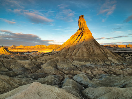 Golden hour on Castil de Tierra with a distant person - Expansive shot of the iconic rock formation in Bardenas Reales with a human element for scale.の写真素材