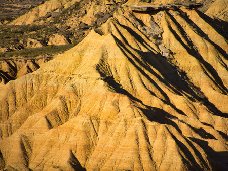 Golden light on unique rock formations in Bardenas Reales - Abstract patterns of an arid landscape, perfect for travel, nature, and geology themes.の写真素材