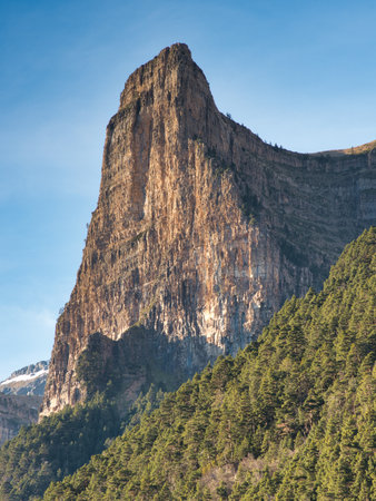 Majestic rock peak framed by trees - A majestic craggy rock peak towers over a forested valley in...