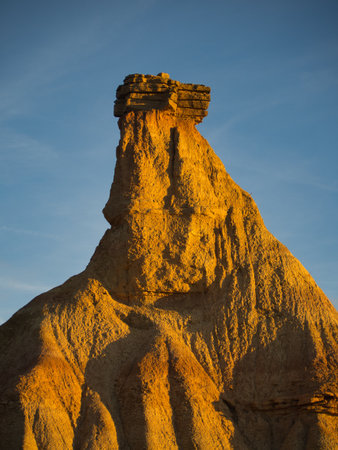 Dramatic eroded desert rock formation at sunset - The distinctive Castil de Tierra formation in Bardenas Reales, Spain, under golden hour light and a clear blue sky.の写真素材