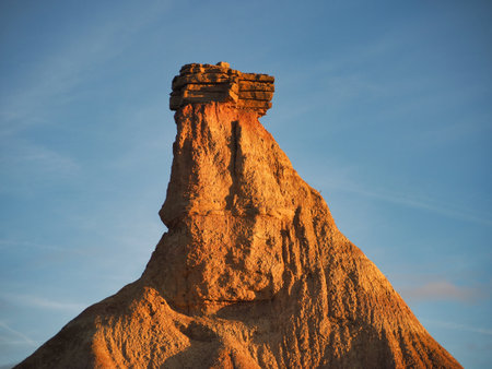 Dramatic eroded desert rock formation at sunset - The distinctive Castil de Tierra formation in Bardenas Reales, Spain, under golden hour light and a clear blue sky.の写真素材