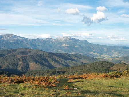 Sweeping mountain range view under a blue sky - A wide-angle landscape of multiple layers of green...
