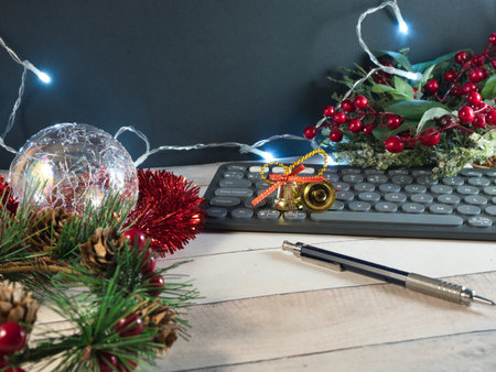 Festive Desk with Christmas Lights - Christmas-themed desk setup with keyboard, glasses, festive ornaments, and string lights on a light wood surface, perfect for holiday work.の写真素材