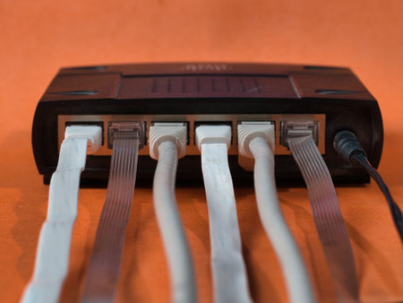Router with Ethernet Cables Orange Background - Close-up of the back of a black network router with...