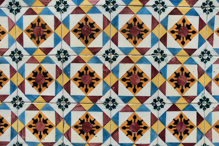 Traditional Portuguese Azulejo Tile Wall - Vibrant close-up of a classic Portuguese azulejo wall featuring blue, yellow, and terracotta geometric patterns and a dark metal drainage detail.の写真素材