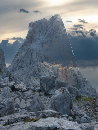 Imposing Naranjo de Bulnes Peak at Sunrise or Sunset - Majestic, vertical limestone wall of Picu Urriellu in Picos de Europa National Park, Spain, under a dramatic blue sky.の写真素材