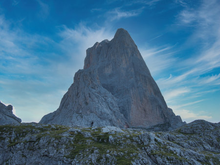 Imposing Naranjo de Bulnes Peak at Sunrise or Sunset - Majestic, vertical limestone wall of Picu Urriellu in Picos de Europa National Park, Spain, under a dramatic blue sky.の写真素材