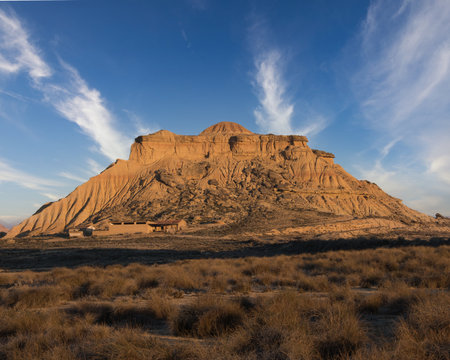 Abstract Desert Badlands Texture at Golden Hour - Striking close-up of eroded clay and sandstone peaks and ridges of badlands under harsh sidelight, creating strong diagonal shadows.の写真素材