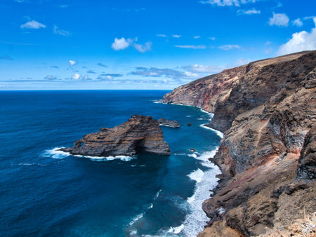 Atlantic Coastal Cliffs with Rock Arch - Dramatic high-angle view of rugged volcanic cliffs meeting the deep blue Atlantic Ocean, featuring a prominent natural rock arch formation.の写真素材