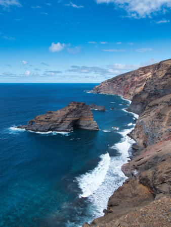 Atlantic Coastal Cliffs with Rock Arch - Dramatic high-angle view of rugged volcanic cliffs meeting the deep blue Atlantic Ocean, featuring a prominent natural rock arch formation.の写真素材