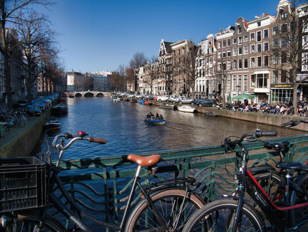 Canal Binnen Amstel Amsterdam Bicycles View - Classic view of a canal in the historic center of Amsterdam, Netherlands, featuring parked bicycles and traditional Dutch houses under a clear blue sky.の写真素材