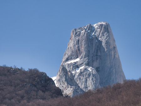 Majestic rock monolith against blue sky - Close-up shot of the stunning Pico Urriellu (Naranjo de Bulnes) in Picos de Europa National Park, Spain, on a bright, sunny day.の写真素材