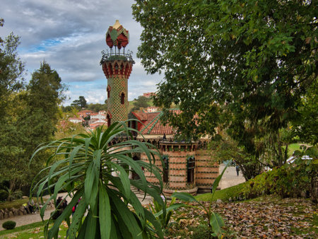 El Capricho de GaudÃ­ from Lush Garden View - View of the elaborate Modernist palace and tower through green foliage and hydrangea flowers under a moody sky.の写真素材