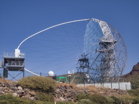 MAGIC Telescope at Roque de los Muchachos Observatory - The MAGIC gamma-ray telescope, a massive reflective dish and metal structure, dominates the landscape at the Roque de los Muchachos Observatory.の写真素材