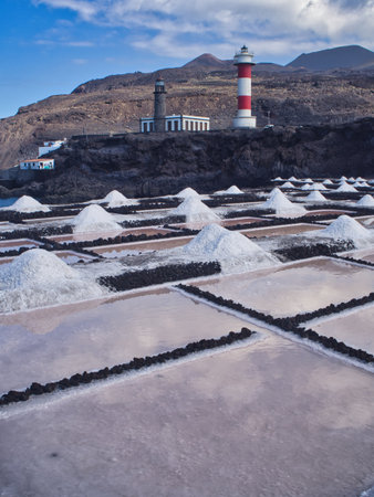 Two lighthouses on volcanic coast with dramatic sky - The old and new lighthouses (Faro de Fuencaliente) standing on volcanic black rock with the volcano in the background under a dramatic cloudy sky.の写真素材