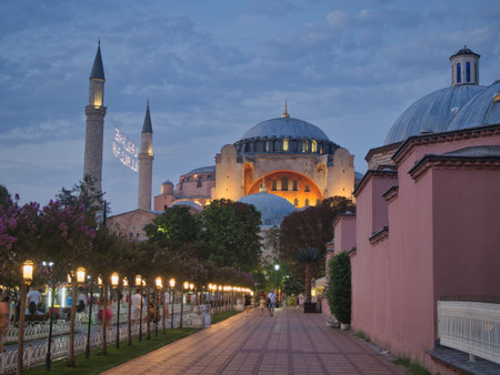 Illuminated Path to Hagia Sophia Dome - Illuminated Hagia Sophia seen in long perspective from a tree-lined pathway with glowing streetlights at twilight in historic Istanbul, Turkey.の写真素材