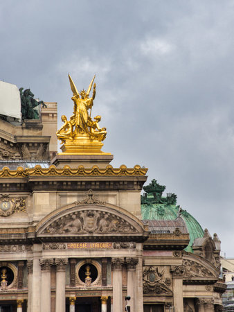OpÃ©ra Garnier Golden Victory Statue Close-up - Detailed shot of the majestic gilded bronze statue 'Harmony' (or 'Poetry') atop the OpÃ©ra Garnier facade in Paris against a moody, cloudy sky.の写真素材