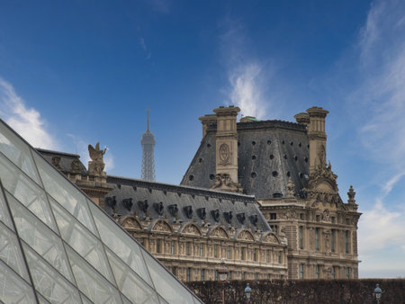 Louvre Pyramid Glass and Palace Architecture - Dramatic close-up showing the geometric glass surface of the Louvre Pyramid contrasting with the ornate stone architecture of the historic palace under a moody sky.の写真素材