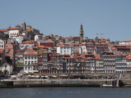 Colorful Houses of Ribeira District along Douro River, Porto - View of the dense, stacked, and colorful historic buildings of the Ribeira district rising from the Douro River bank, with tourist boats moored below.の写真素材