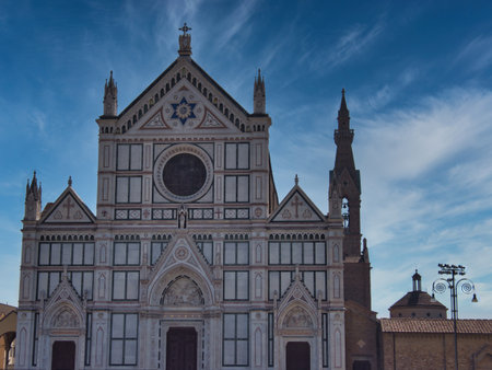 Santa Croce Basilica Neo-Gothic Marble Facade - The ornate white, pink, and green marble facade of the historic Basilica di Santa Croce and its bell tower against a dramatic blue sky in Florence, Italy.の写真素材