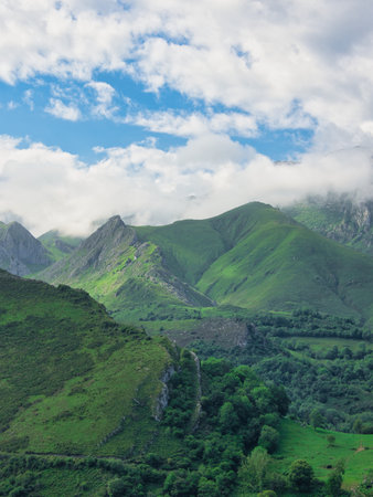 Lush green Picos de Europa rolling hills - Wide landscape view of a verdant mountain range with...