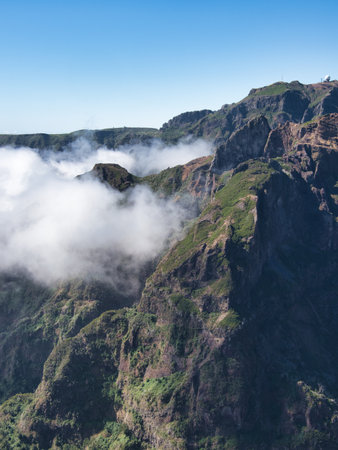 Dramatic Madeiran Mountain Peaks and Clouds - Vertical view of rugged volcanic peaks covered in green vegetation, with low clouds rolling through the deep valleys.の写真素材