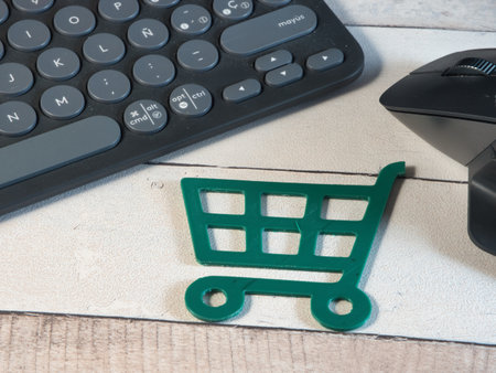 Online Shopping: Keyboard, Mouse, Cart - Overhead view of a miniature green shopping cart with a computer keyboard and mouse. Represents the convenience and technology of online commerce and digital retail.の写真素材