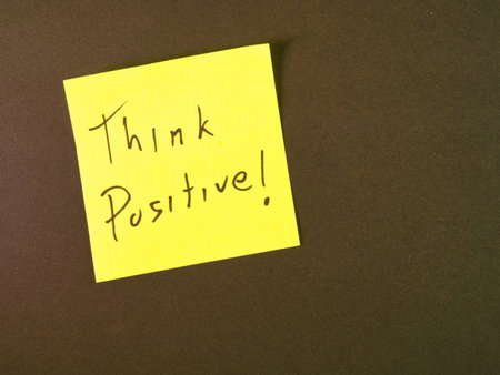 Think Positive! Sticky Note Reminder - Bright yellow sticky note with 'Think Positive!' message on dark background. Inspiring reminder for optimism, motivation, and a positive mindset.の写真素材