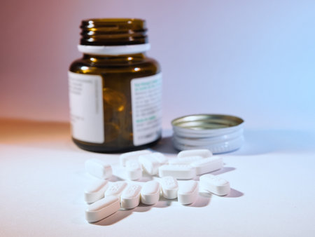White Pills Spilled from Medicine Bottle - White oblong medication pills spilled from a brown glass bottle, with the screw cap nearby. Concept of health, medicine, treatment, and pharmaceuticals.の写真素材