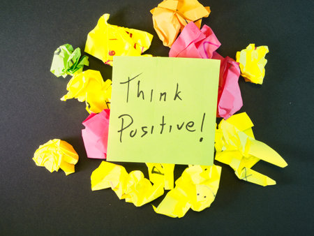 Think Positive! Note Amidst Crumpled Papers - An uplifting 'Think Positive!' sticky note surrounded by colorful crumpled papers on a dark background, symbolizing idea generation, challenges, and resilience.の写真素材