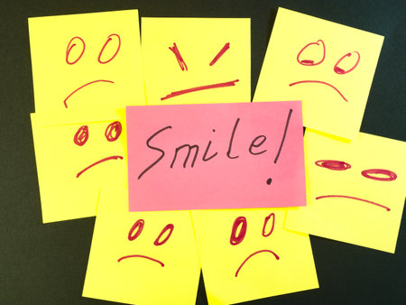 Smile Among Sad Faces Sticky Notes - A pink sticky note with 'Smile!' stands out among yellow notes...