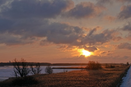Sunset over reed and a frozen lake
