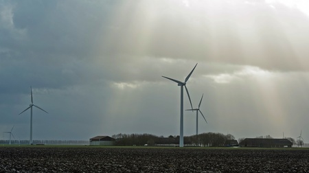Sunbeams over farm and wind turbines