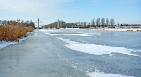 Bridge over a frozen canal in winterの写真素材