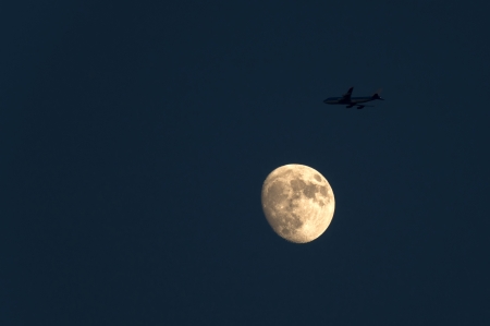 Airliner flying along the moon in dusk
